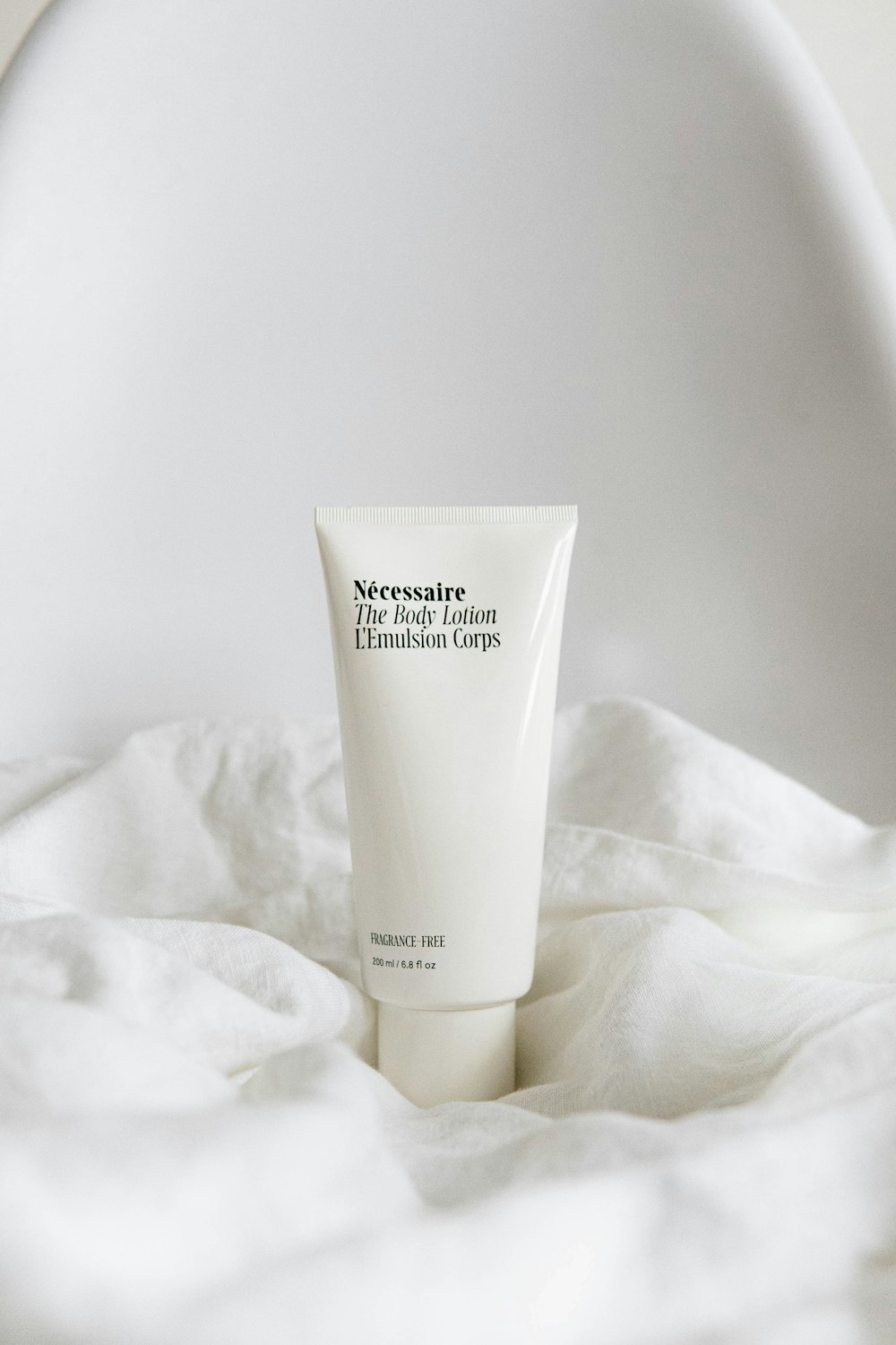 Spa-style scene: body lotion standing in rumpled white linen